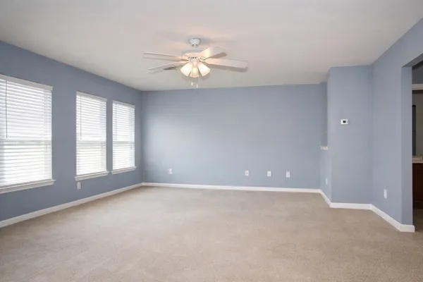 an empty room with windows and chandelier fan