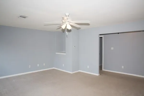 an empty room with a fan & a ceiling fan