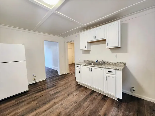 a kitchen with granite countertop white cabinets and wooden floor