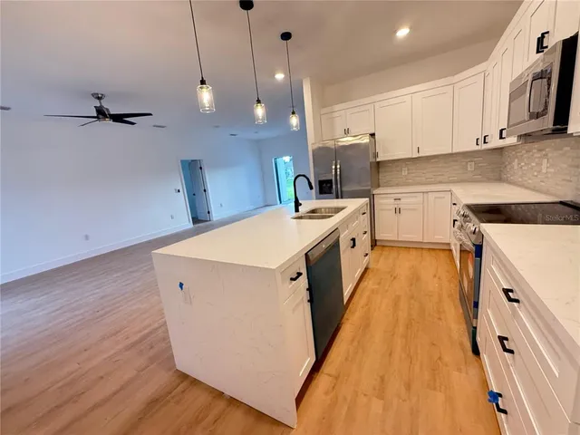 a kitchen with a sink a wooden floor and white cabinets