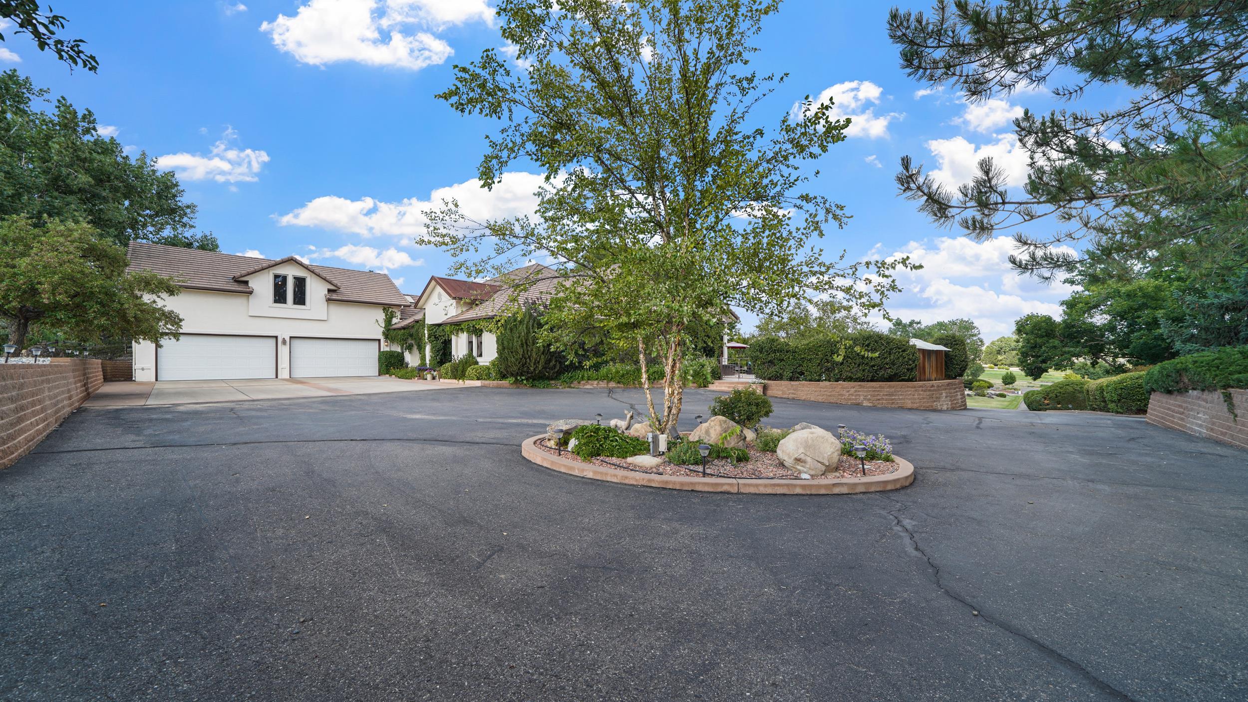 815 25 Road Grand Junction, CO 81505 - Photo 4 of 42 a view of a white house with a big yard and a large tree