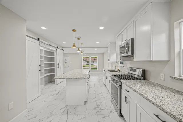 a kitchen with stainless steel appliances granite countertop a sink stove and cabinets