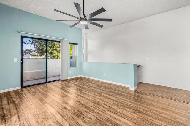 an empty room with wooden floor fan and windows