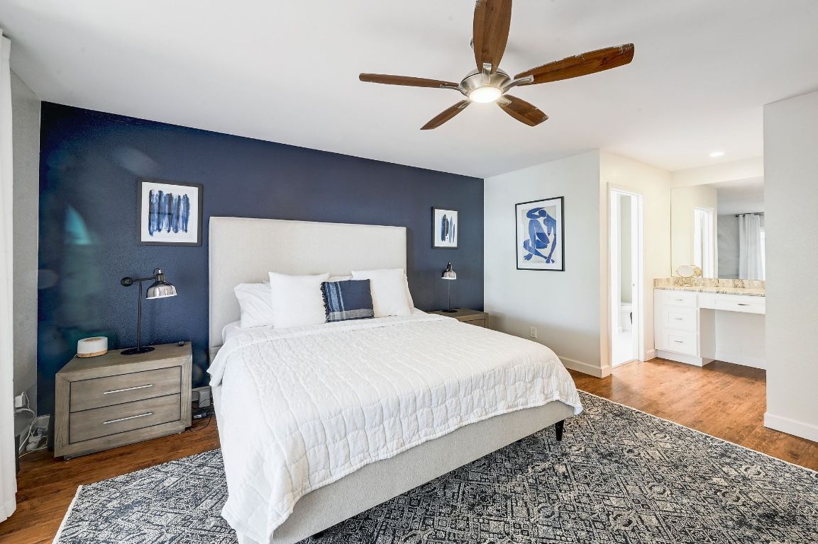 409 Seawind Lakeway, TX 78734 - Photo 13 of 18 a bedroom with a bed ceiling fan and a wooden floor