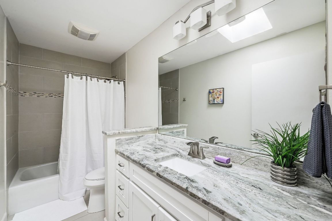 409 Seawind Lakeway, TX 78734 - Photo 16 of 18 a bathroom with a granite countertop sink a toilet a mirror and shower