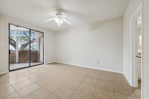 an empty room with fan and large windows