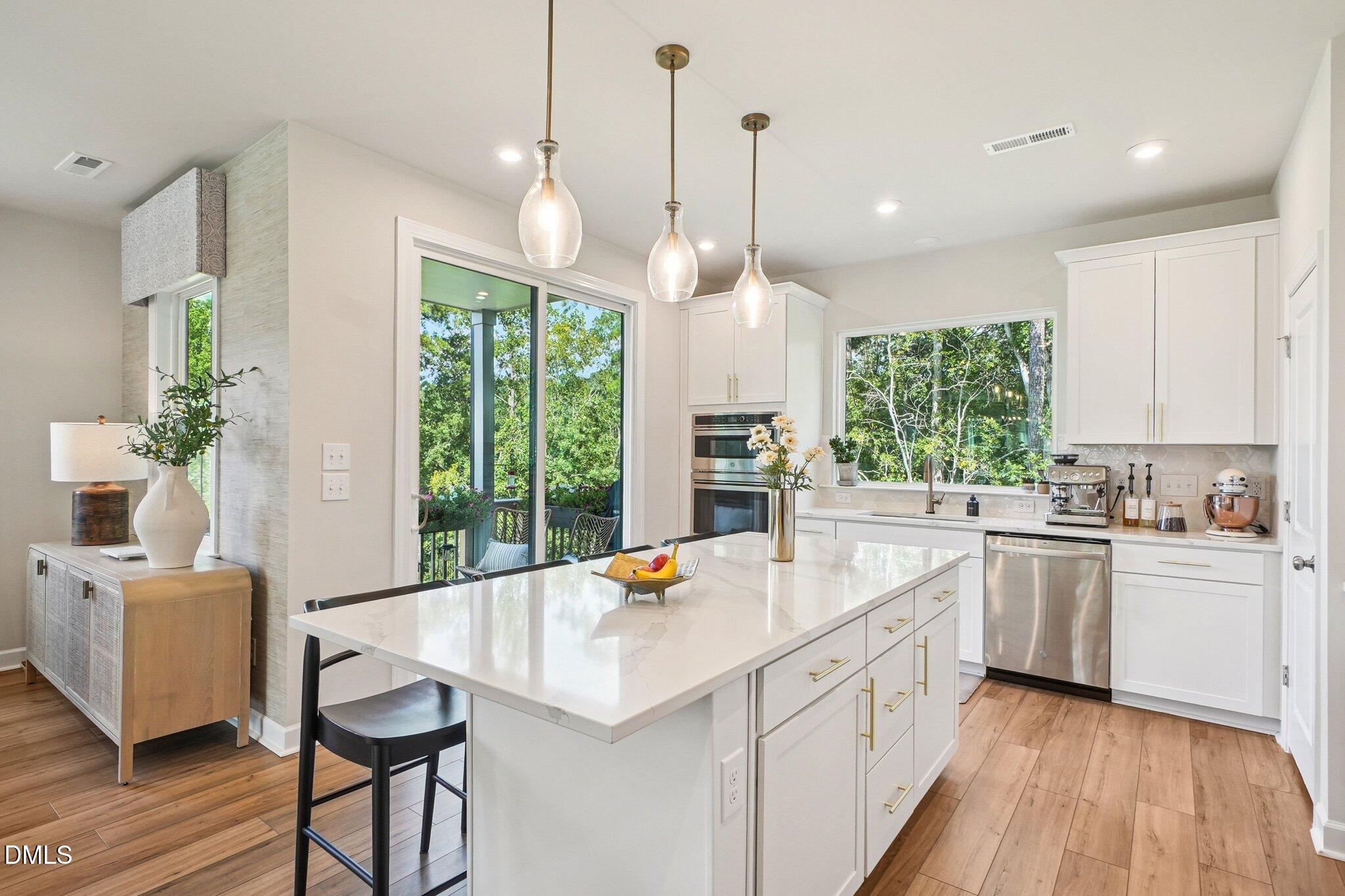 4822 Cypress Tree Lane Raleigh, NC 27612 - Photo 10 of 28 a kitchen with a stove a sink a kitchen island with stainless steel appliances granite countertop lots of white cabinets a dining table and chairs