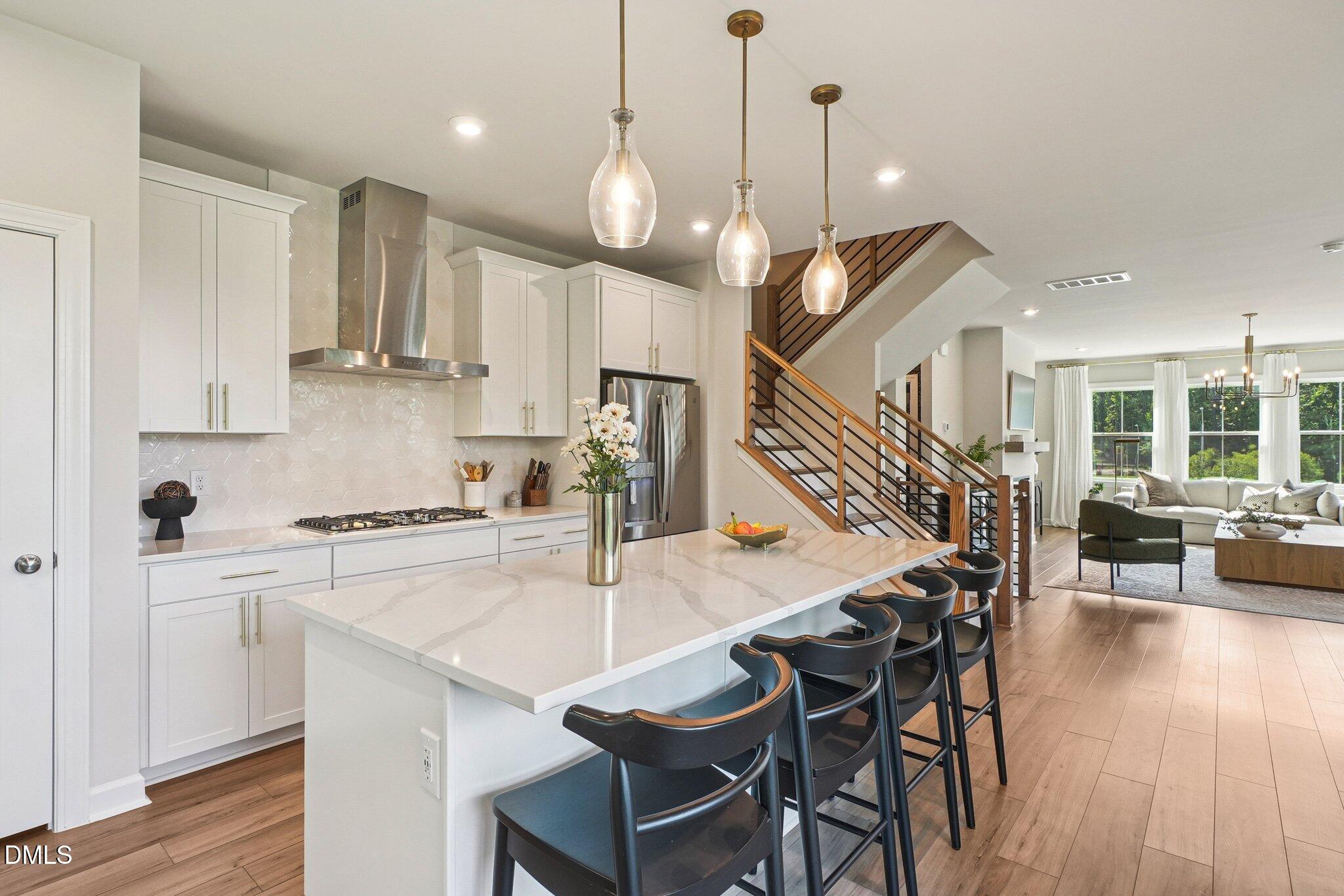 4822 Cypress Tree Lane Raleigh, NC 27612 - Photo 12 of 28 a open kitchen with stainless steel appliances granite countertop a stove a refrigerator a kitchen island a dining table and chairs with wooden floor
