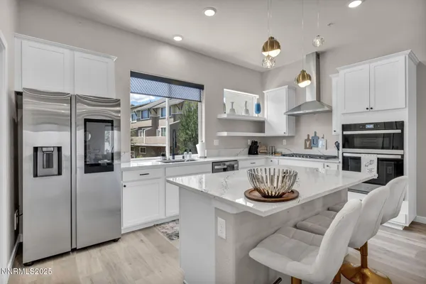 a kitchen with stainless steel appliances granite countertop a stove a sink a refrigerator and white cabinets
