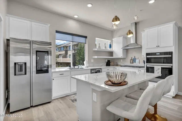 a kitchen with stainless steel appliances granite countertop a stove a sink a refrigerator and white cabinets