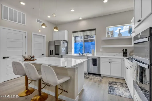 a large white kitchen with a stove a sink dishwasher and a refrigerator with wooden floor