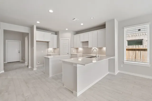 a large white kitchen with kitchen island a sink stainless steel appliances and cabinets