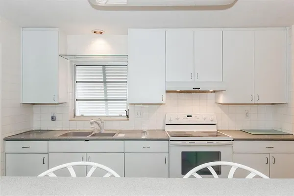 a kitchen with granite countertop white cabinets and white appliances