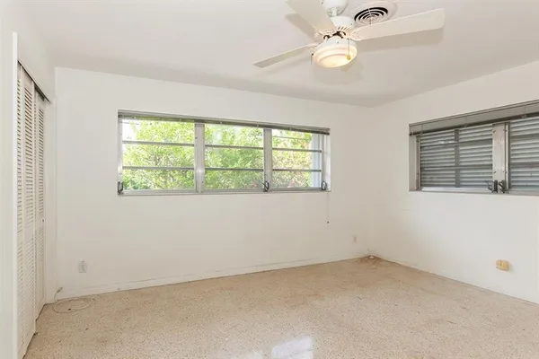 an empty room with a window and a fan