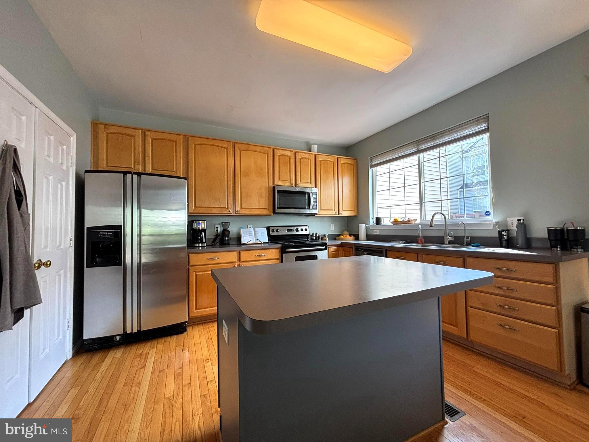 6659 Patent Parish Lane Alexandria, VA 22315 - Photo 4 of 16 a kitchen with stainless steel appliances granite countertop a refrigerator a sink dishwasher a stove and a microwave oven with wooden floor