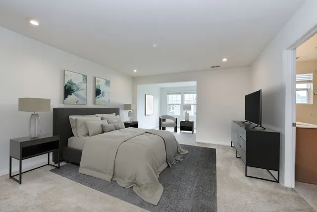 a spacious bedroom with a bed and a flat screen television