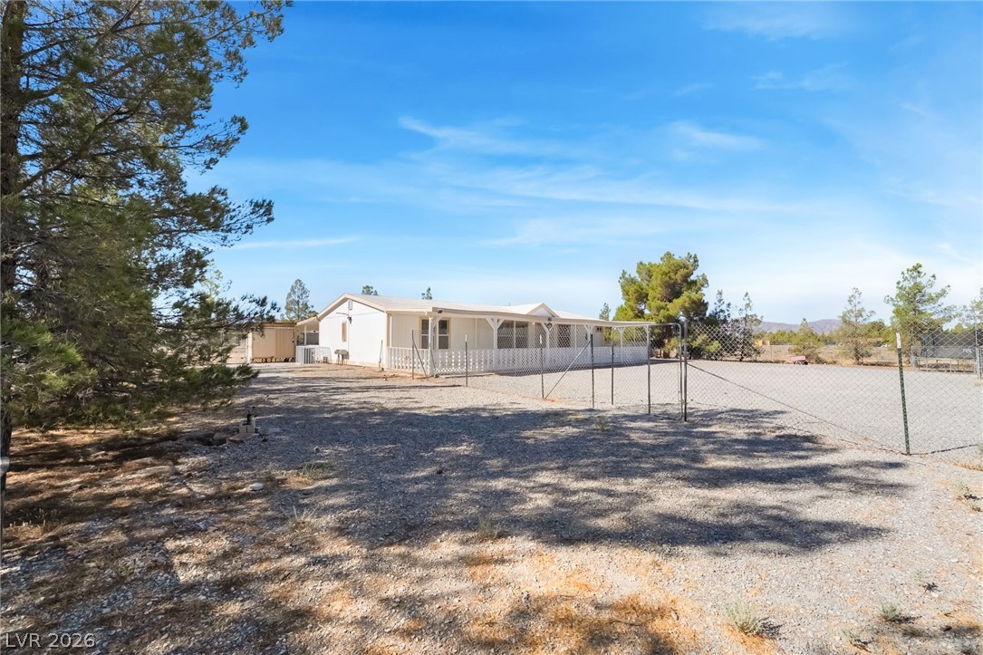 1551 West Wilson Road Pahrump, NV 89048 - Photo 5 of 68 Mature trees shade the gravel entry of this gated desert estate under blue skies.