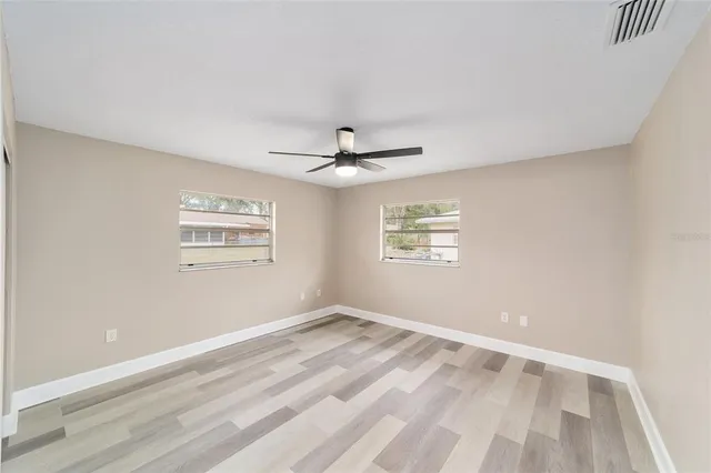 an empty room with windows and ceiling fan