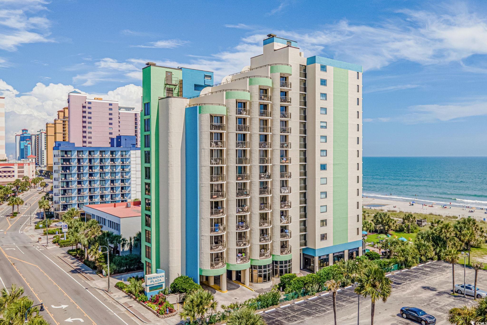 View of apartment building / complex featuring view of water and beach