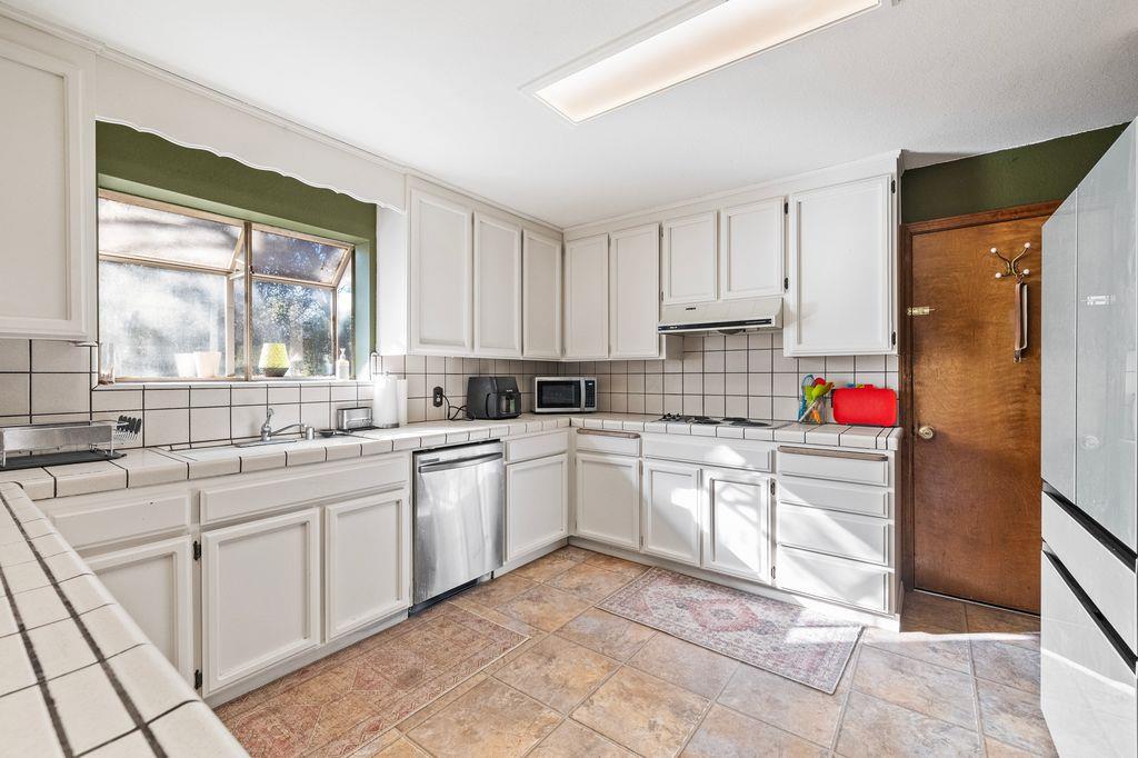 1480 Pennsylvania Gulch Road Murphys, CA 95247 - Photo 14 of 31 a kitchen with kitchen island granite countertop white cabinets sink and a window