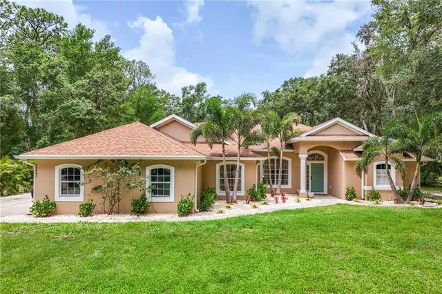 a front view of a house with a garden and trees