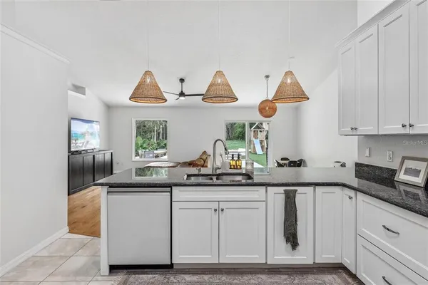 a kitchen with white cabinets and window
