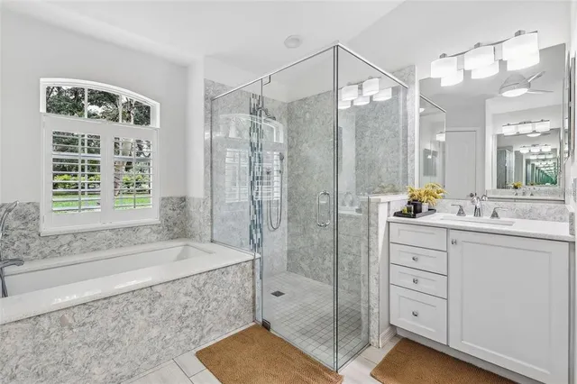 a bathroom with a granite countertop sink a mirror a bathtub and shower