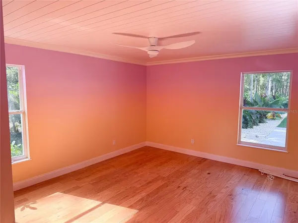 a view of empty room with wooden floor and fan
