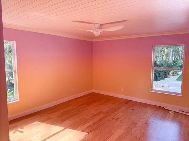 a view of empty room with wooden floor and fan