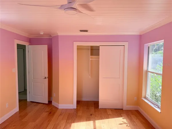a view of empty room with wooden floor and fan