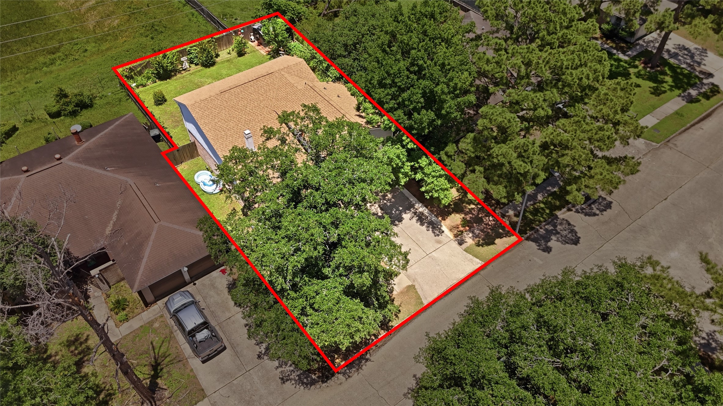 4718 Temple Bell Drive Spring, TX 77388 - Photo 43 of 50 This aerial photo shows a single-story home with a tan roof, set on a well-defined plot marked in red. It features a spacious driveway and a lush, landscaped yard with mature trees, offering privacy and shade. The property is situated in a quiet neighborhood with nearby green space.