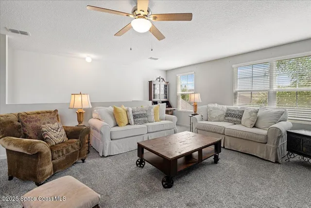 a living room with furniture a ceiling fan and a window