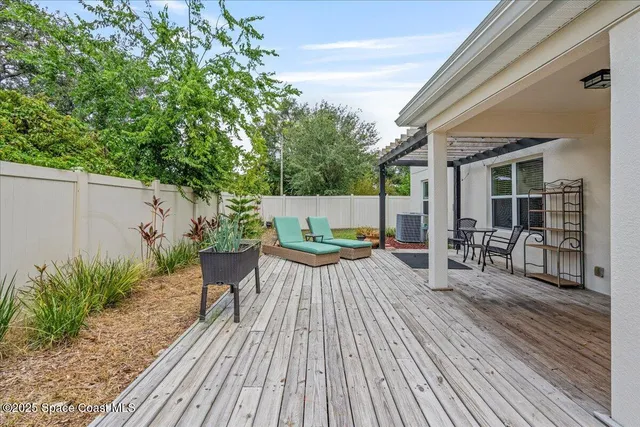 a view of a patio with table and chairs potted plants with wooden floor and fence