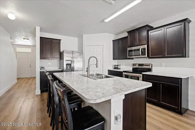 a kitchen with stainless steel appliances granite countertop a stove a sink dishwasher a refrigerator with a dining table and chairs