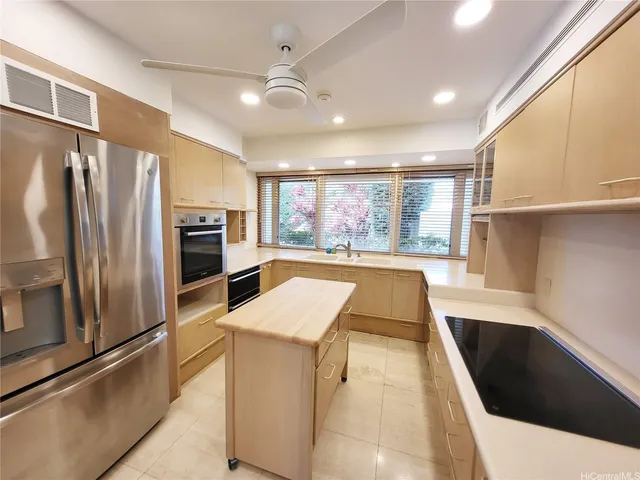 a large kitchen with stainless steel appliances kitchen island a large counter top and a refrigerator