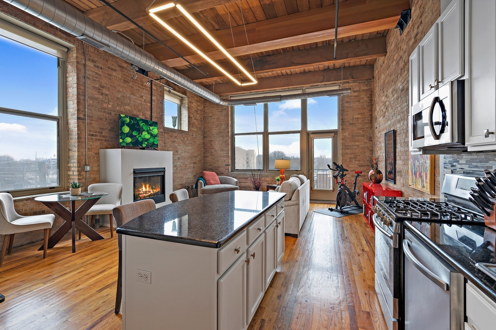 1500 West Monroe Street, Unit 401 Chicago, IL 60607 - Photo 3 of 24 a kitchen with stainless steel appliances granite countertop a stove a refrigerator a dining table and chairs with wooden floor
