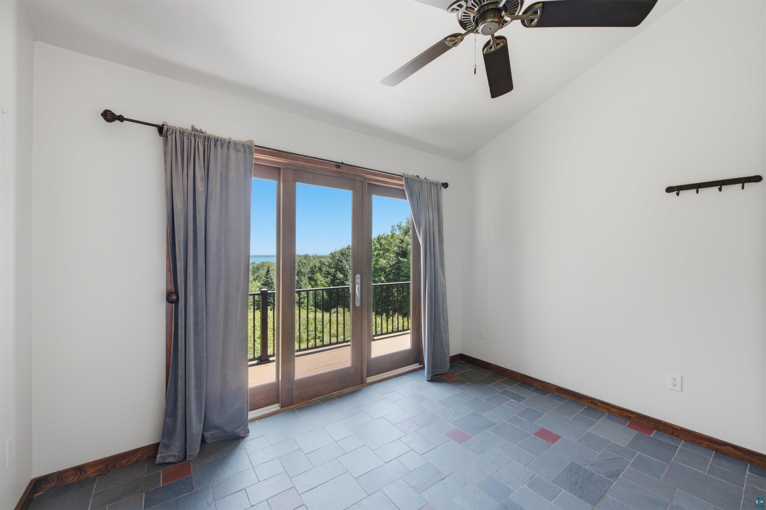 86270 Meyers-Olson Road Bayfield, WI 54814 - Photo 17 of 33 Room featuring wood-frame glass doors opening to a balcony, a ceiling fan, and slate tile flooring