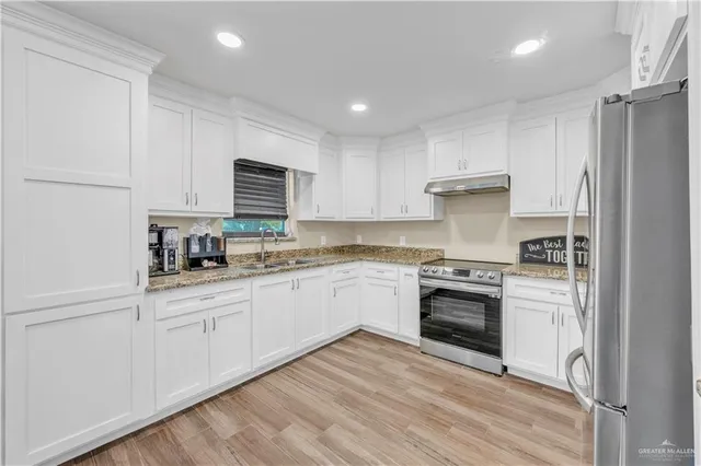 a kitchen with granite countertop a stove top oven sink and cabinets
