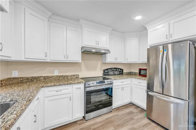 a kitchen with white cabinets and stainless steel appliances
