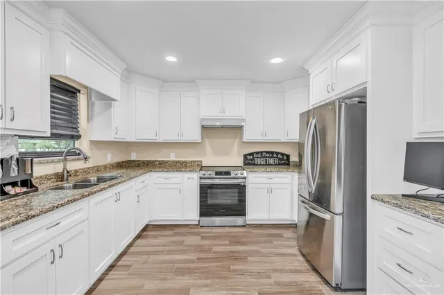 a kitchen with granite countertop stainless steel appliances a sink cabinets and a window