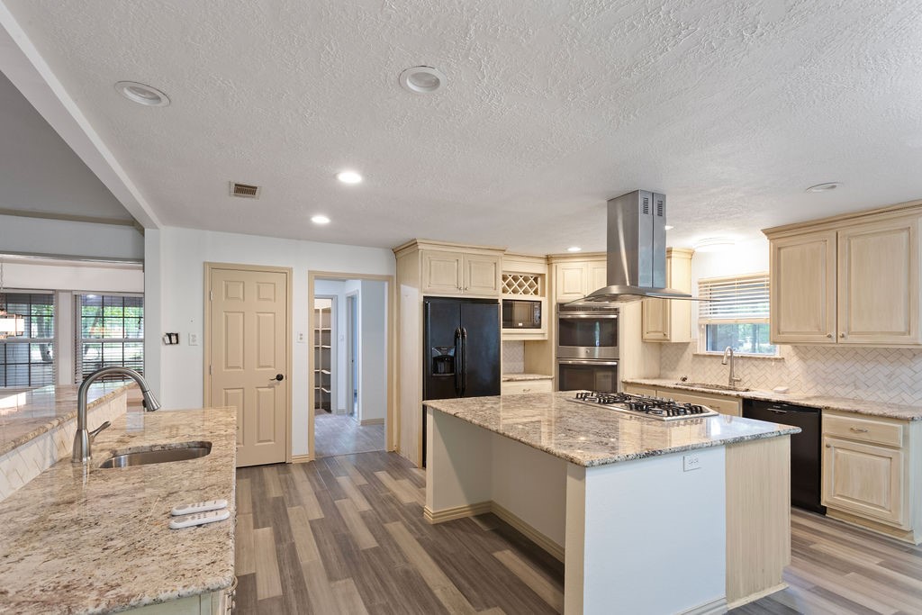 15050 Cardinal Trail Conroe, TX 77302 - Photo 7 of 44 a kitchen with granite countertop kitchen island wooden floors and stainless steel appliances
