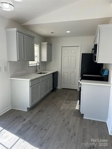 a kitchen with a sink and wooden floor