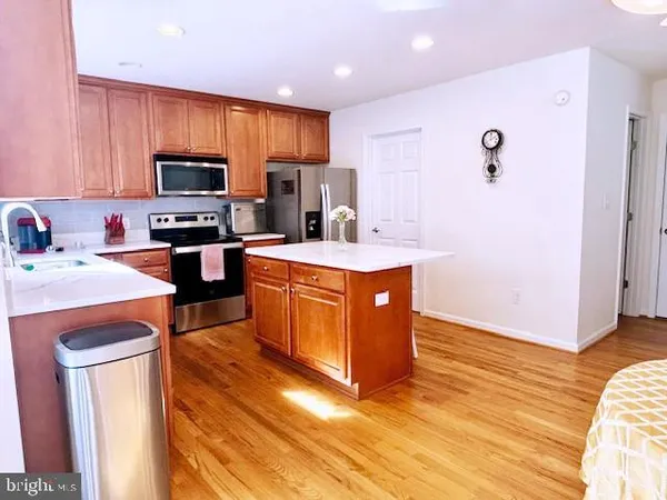 a kitchen with stainless steel appliances granite countertop a stove top oven a sink dishwasher a refrigerator and cabinets with wooden floor