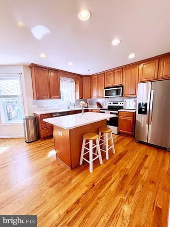 a kitchen with stainless steel appliances granite countertop a stove top oven a sink dishwasher a dining table and chairs with wooden floor
