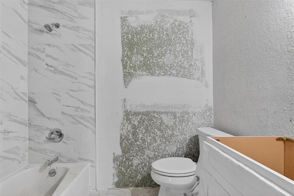 1212 Manning Road Benbrook, TX 76126 - Photo 11 of 20 White bathtub with chrome fixtures and large-format marble-look wall tiling