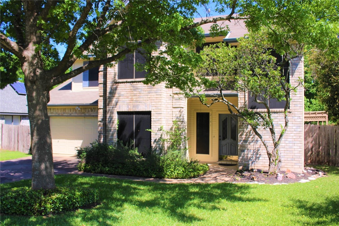 a front view of a house with a yard and tree