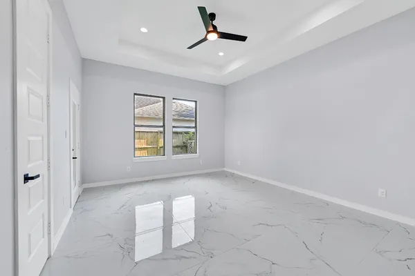 an empty room with windows and fan