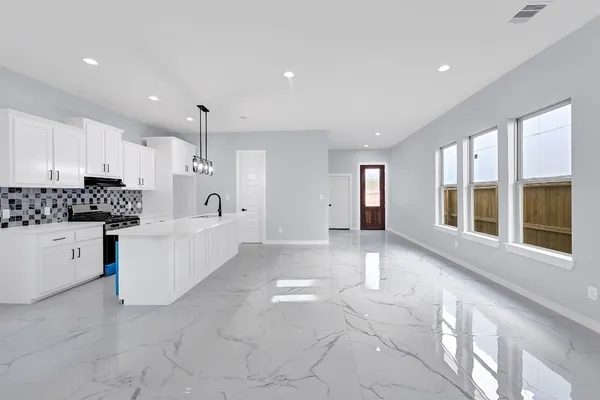 a large white kitchen with center island and stainless steel appliances