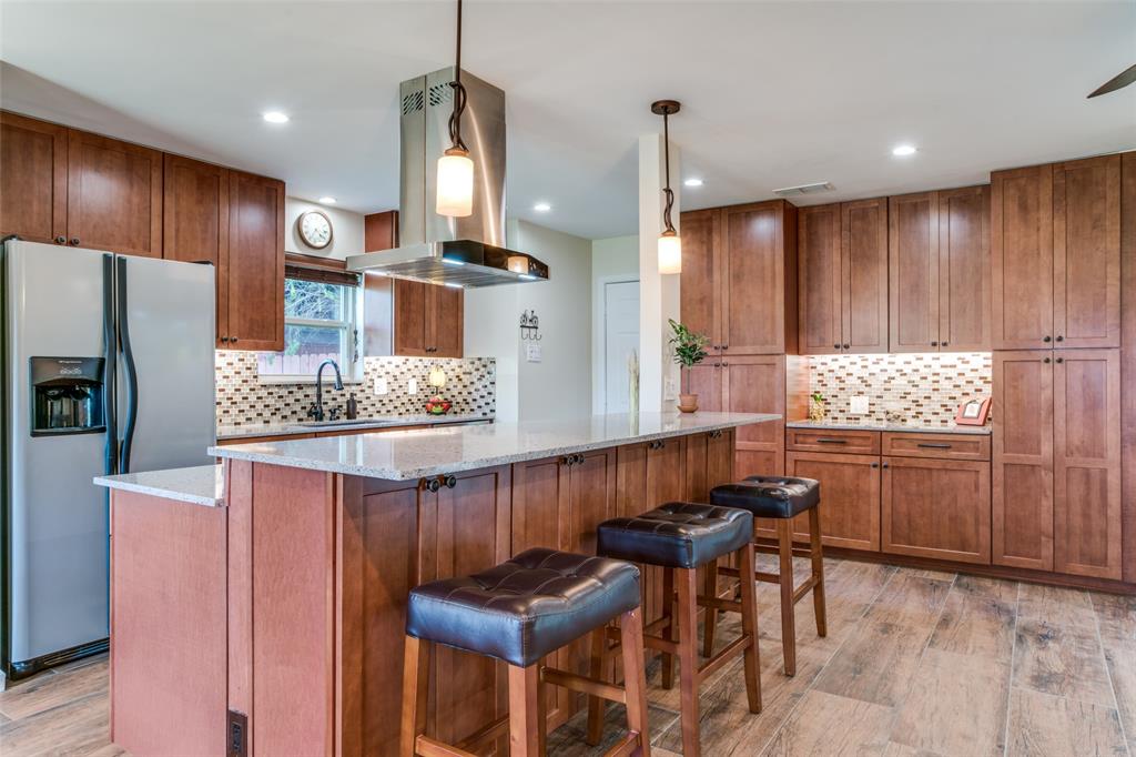 a kitchen with granite countertop a table chairs stove a refrigerator and cabinets
