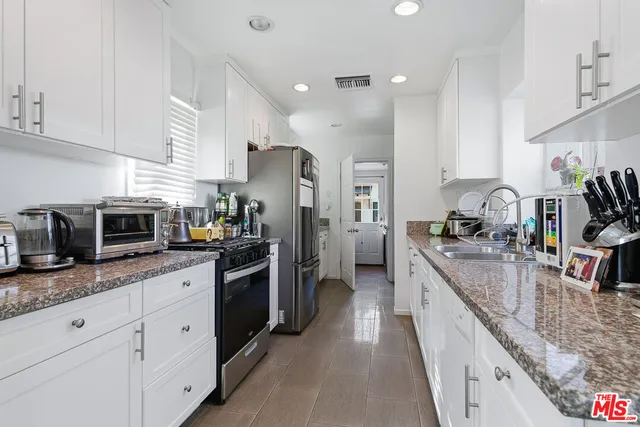a large kitchen with stainless steel appliances granite countertop a sink stove and refrigerator